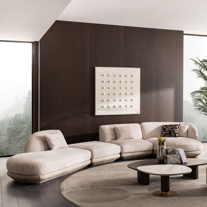 Modern living room with a beige sectional sofa, round coffee table, and abstract wall art.