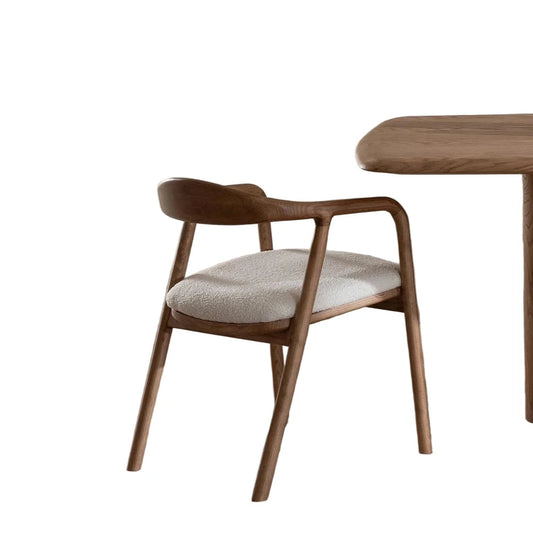 Hard wood chair with cushioned seat next to a wooden table in a minimalistic room.