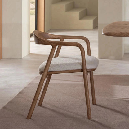 Wooden chair with white cushion next to a wooden table in a minimalistic room.